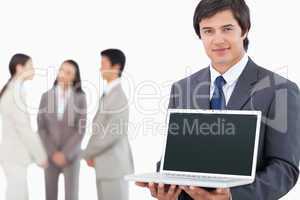 Salesman showing laptop screen with colleagues behind him