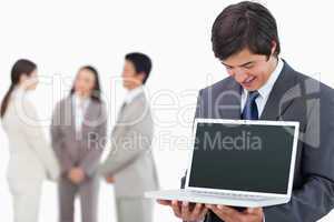Salesman showing laptop screen with team behind him