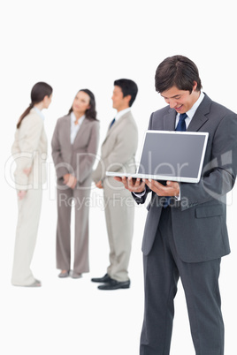 Salesman showing notebook screen with team behind him