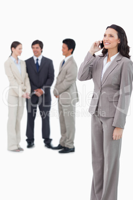 Saleswoman on the cellphone with team behind her