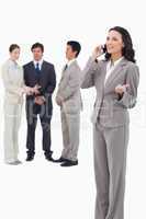Saleswoman talking on cellphone with colleagues her