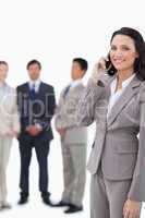 Smiling saleswoman on cellphone with team behind her