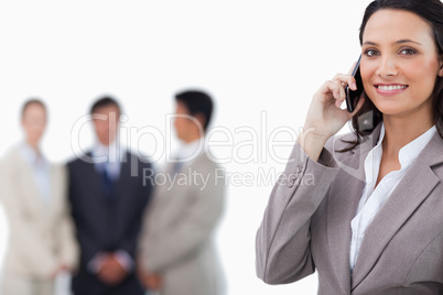 Smiling saleswoman on mobile phone with colleagues behind her