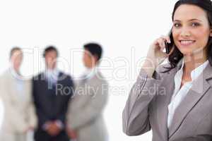 Smiling saleswoman on mobile phone with colleagues behind her
