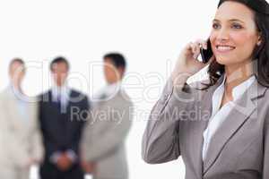 Smiling saleswoman on her mobile phone with team behind her