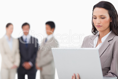 Saleswoman with laptop and colleagues behind her