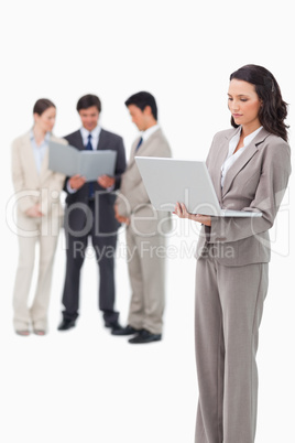 Standing saleswoman with notebook and colleagues behind her