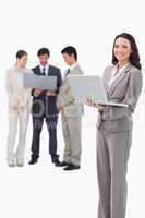 Smiling saleswoman with laptop and associates behind her