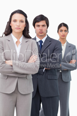 Serious salesteam standing together with arms folded