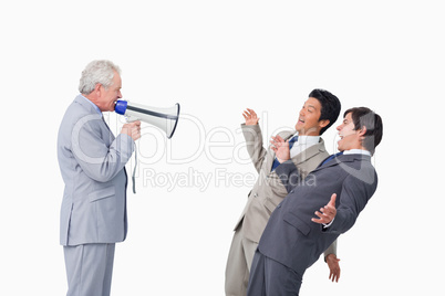 Senior businessman with megaphone yelling at his employees