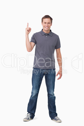 Smiling young man pointing up