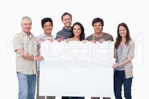 Smiling group holding blank sign together