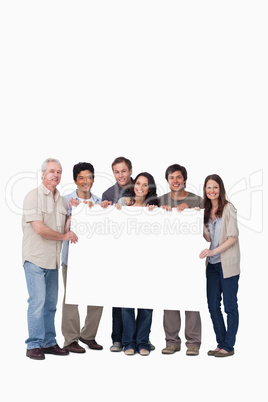 Smiling group of friends holding blank sign together