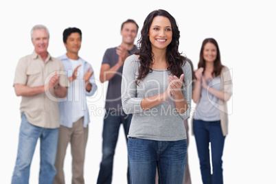 Clapping young woman with friends behind her