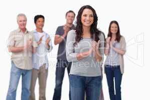 Clapping young woman with friends behind her