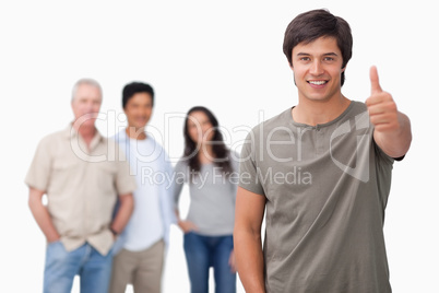 Smiling man with friends behind him giving thumb up