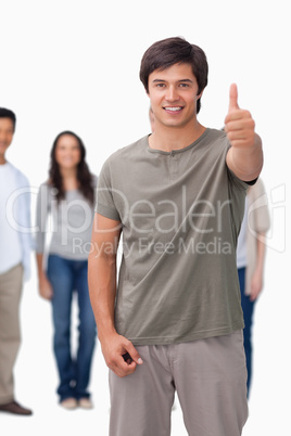 Smiling man giving thumb up with friends behind him