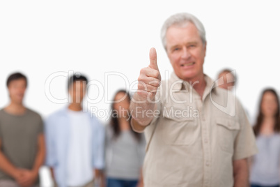 Thumb up given by mature man with young people behind him