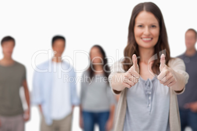Thumbs up given by smiling woman with friends behind her