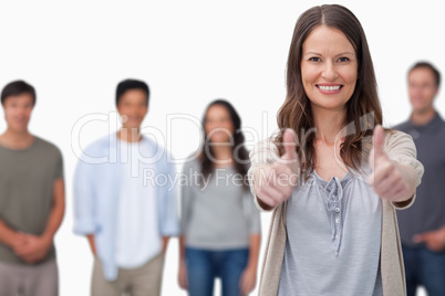 Smiling woman with friends behind her giving thumbs up