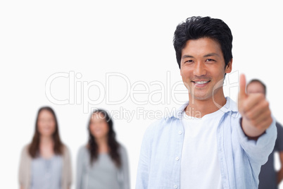 Smiling male with friends behind him giving thumb up