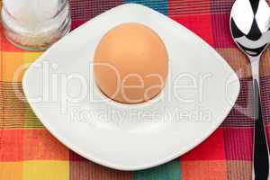 Frühstücksei im Eierbecher mit Salzmühle und Löffel