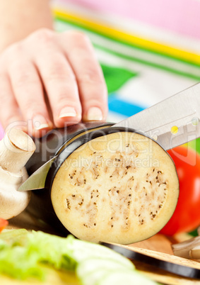 Woman's hands cutting aubergine eggplant