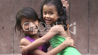 Happy little Asian girl hugging female baby and smiling