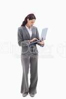 Businesswoman standing and typing on a laptop
