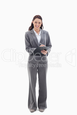 Businesswoman smiling while writing on a clipboard