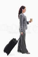 Profile of a businesswoman with a suitcase and holding a coffee