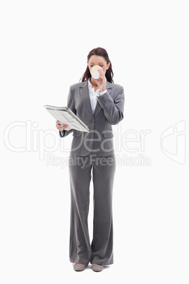 Businesswoman drinking a coffee and reading a newspaper