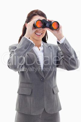 Close-up of a businesswoman smiling and looking through binocula