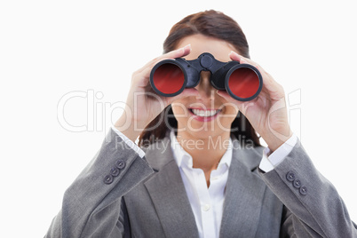 Businesswoman smiling and looking through binoculars