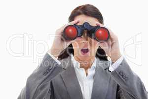 Close-up of a surprised businesswoman looking through binoculars