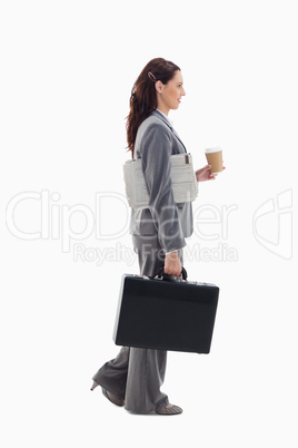 Profile of a businesswoman walking with a briefcase, newspaper a