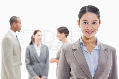 Businesswoman smiling with co-workers in the background