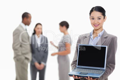Businesswoman smiling showing a laptop screen with co-workers in