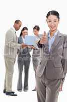 Businesswoman smiling and approving with co-workers in the backg