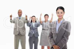 Businesswoman smiling with co-workers approving in the backgroun