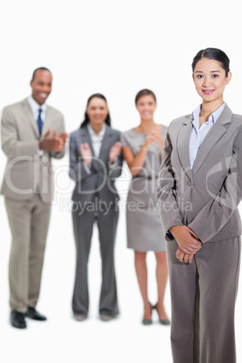 Close-up of a businesswoman with co-workers applauding in the ba