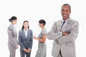 Businessman smiling with three co-workers talking in the backgro