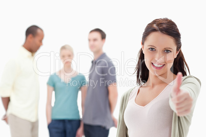 Close-up of a woman smiling and giving the the thumbs-up with fr