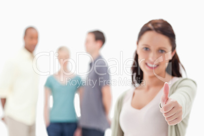 Close-up of a woman giving the thumbs-up with friends