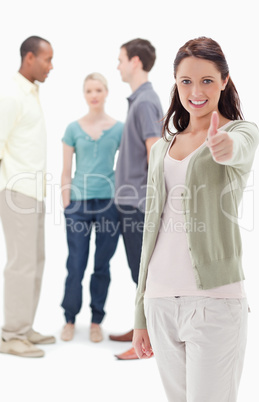 Girl smiling and giving the thumbs-up with friends