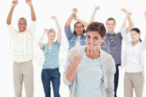 Woman clenching her fist with people behind raising their arms