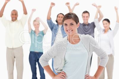 Woman smiling with her hands on her hips with people behind rais