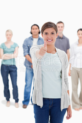 Close-up of a woman giving the thumb-up with people behind