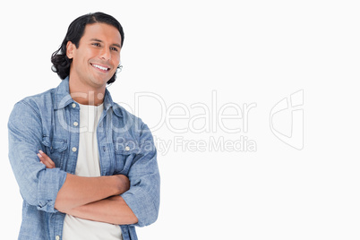 Close-up of a smiling man crossing his arms and looking towards