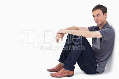 Close-up of a man sitting against a wall